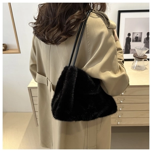 Rear view of a black faux fur shoulder bag with slender leather straps on a model