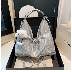 Close-up of metallic silver pleated hobo bag with a cute white cloud plush pendant