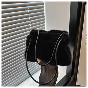 Close-up of black fluffy faux fur shoulder bag with leather straps in soft natural light
