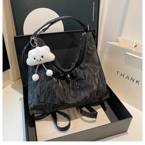 Detail of black pleated tote bag with a cute white cloud plush charm in a gift box