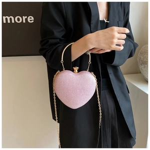 Dettaglio della clutch a cuore con paillettes rosa e manico dorato tenuta da modella