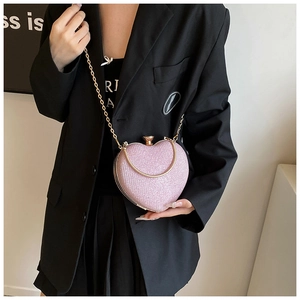 Close-up of pink heart-shaped evening bag with glitter texture and gold chain strap