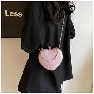 Close-up of pink sequined heart bag with gold chain strap on a black blazer model