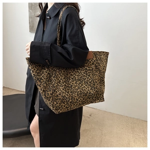 Detailed side view of large leopard print canvas tote bag with brown leather accents