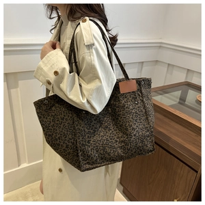 Close-up of leopard print canvas tote bag with brown leather patch and shoulder strap