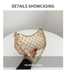 Detail view of cream crescent bag with vintage pattern and gold chain strap