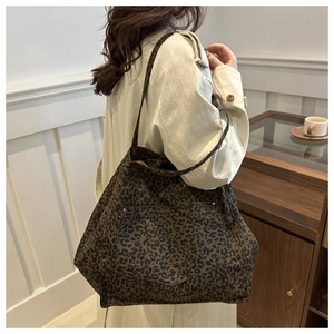Détail du grand sac cabas léopard avec rivets argentés et poche frontale porté à l'épaule