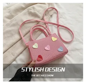 Detailed texture of pink corduroy handbag featuring colorful heart-shaped appliqués