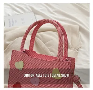 Detail shot of a red woven handbag with colorful leather heart patches and round handles