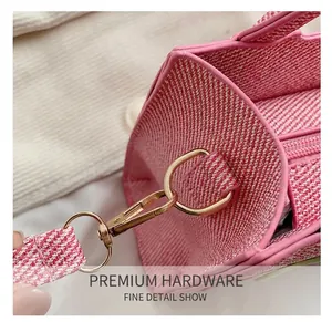 Close-up of pink tweed fabric texture with premium gold metal hook on crossbody bag