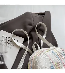 Detail of white textured backpack with colorful stripe accents and thin shoulder straps
