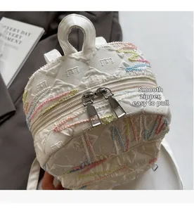Close-up of smooth silver metal double zippers and colorful wavy stitching on white quilted backpack