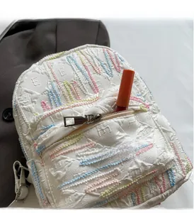 Detail of white bubble textured backpack with colorful embroidery and front zipper pocket