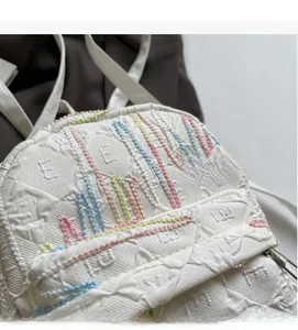 Close-up of white backpack fabric featuring raised letter textures and colorful embroidery