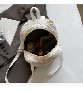 Internal view of a white quilted mini backpack showing space for a phone and cosmetics