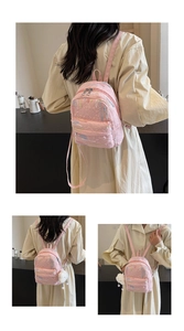 Multiple views of a pink quilted backpack with colorful embroidery and white plush charm