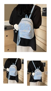 Detail of light blue textured backpack with embroidery and white cloud plush charm