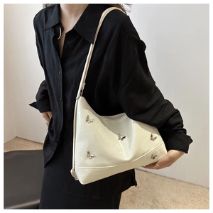 Detail of cream faux crocodile texture shoulder bag with silver butterfly charms