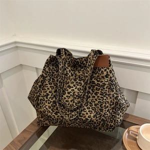 Large capacity leopard print tote bag with brown leather label on a minimalist wooden table