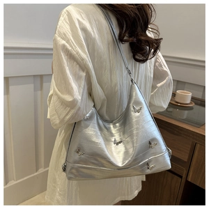 Detail of silver metallic shoulder bag featuring quilted stitching and 3D butterfly accents