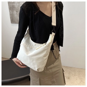 Detailed view of a white half-moon crossbody bag with woven cord knot and wide strap