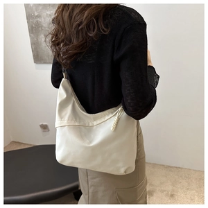 Side view of an off-white half-moon tote bag worn by a model in casual streetwear