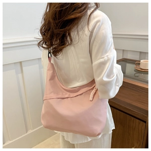 Pink nylon hobo tote bag shown on shoulder with side braided knot zipper detail