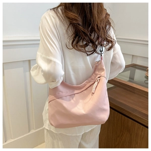 Back view of a woman wearing a light pink nylon hobo bag with a minimalist casual style