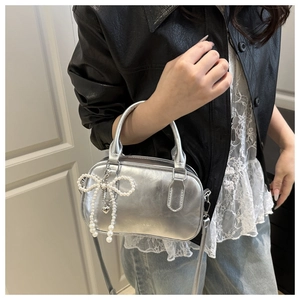 Detail of silver mirrored bowling bag with pearl bow charm and detachable shoulder strap