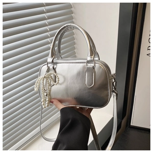 Close-up of silver metallic handbag with pearl bow charm and FASHION & BAG lettering