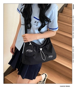 Detail of black drawstring crossbody bag with detachable round coin purse and FASHION logo