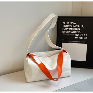 Detail showing white patent leather bucket bag with vibrant orange shoulder strap contrast