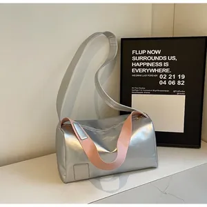 Detail of silver metallic cylindrical shoulder bag with contrasting pink strap accent
