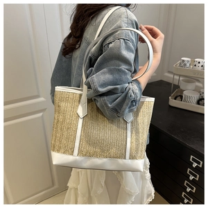 Vue détaillée d'un sac cabas en paille avec bordure en cuir blanc sur un mannequin