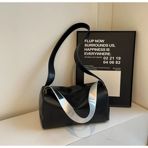 Detail of black cylindrical tote bag with silver metallic strap and matte leather texture