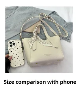 Détail du sac seau en cuir litchi blanc cassé avec foulard et téléphone pour la taille