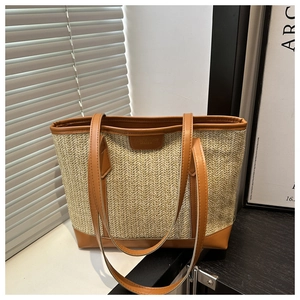 Détail du sac cabas en paille avec anses en cuir marron et texture tissée beige