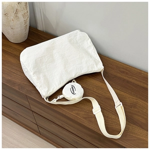 Close-up of white nylon crossbody bag with textured fabric and round coin purse accessory