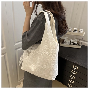 Close-up of white lace floral embroidery on a large capacity canvas tote bag for women