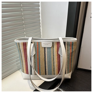 Détail d'un sac cabas tissé à rayures colorées avec garniture en cuir blanc et logo