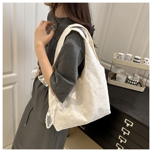 Detailed close-up of white floral lace embroidery on a feminine canvas tote bag