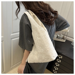 Close-up of white lace embroidery and floral patterns on this large shoulder tote bag