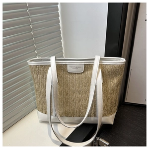 Détail d'un cabas en paille tressée avec anses en cuir blanc et écusson logo mode