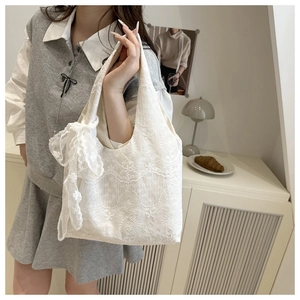 Close-up of white floral embroidery lace tote bag with large decorative bow on handle
