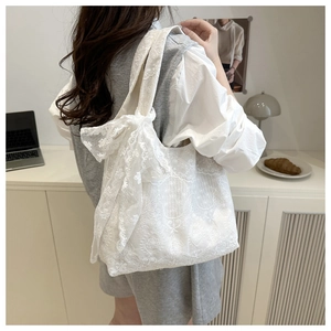 Detailed view of the white floral lace tote bag featuring a large decorative side bow
