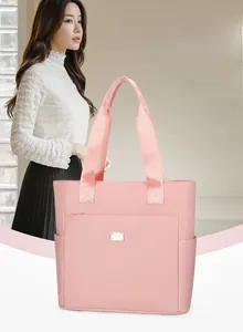 Detail of light pink waterproof nylon tote bag showing side pockets and metal nameplate