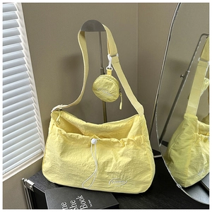Close-up of bright yellow nylon crossbody bag with mini pouch and drawstring detail