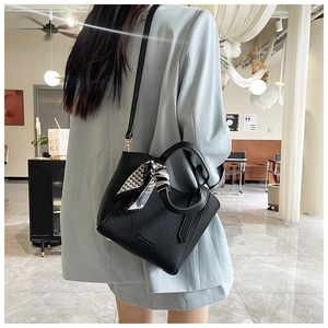 Détail du sac seau noir en cuir grainé avec foulard en soie enroulé sur la poignée