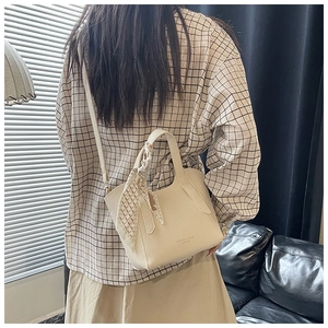 Détail du sac seau en cuir grainé blanc cassé avec ruban décoratif en soie sur la poignée