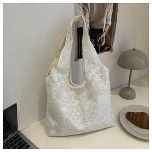 Detail shot of white lace tote bag with floral embroidery and textured fabric